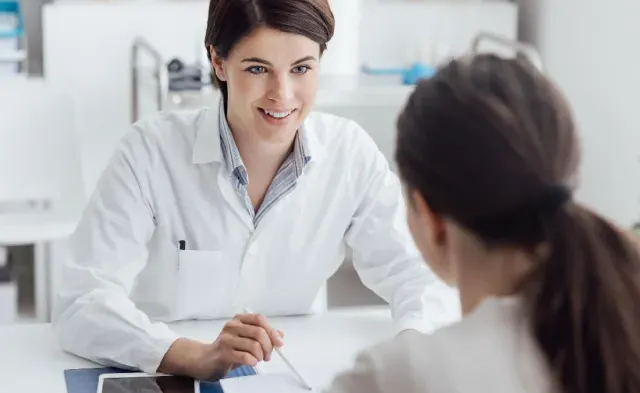 Adult-Gerontology Nurse Practitioner (AGNP) discussing treatment plan with patient and smiling